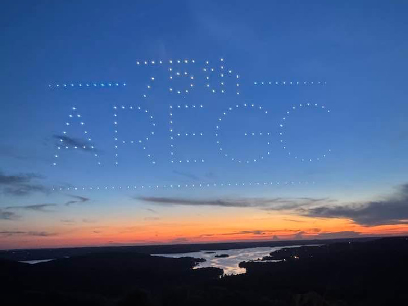 Drones creating words and pictures across a sunset
