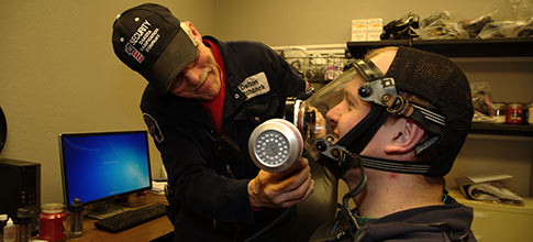 Man adjusting another man's gas mask